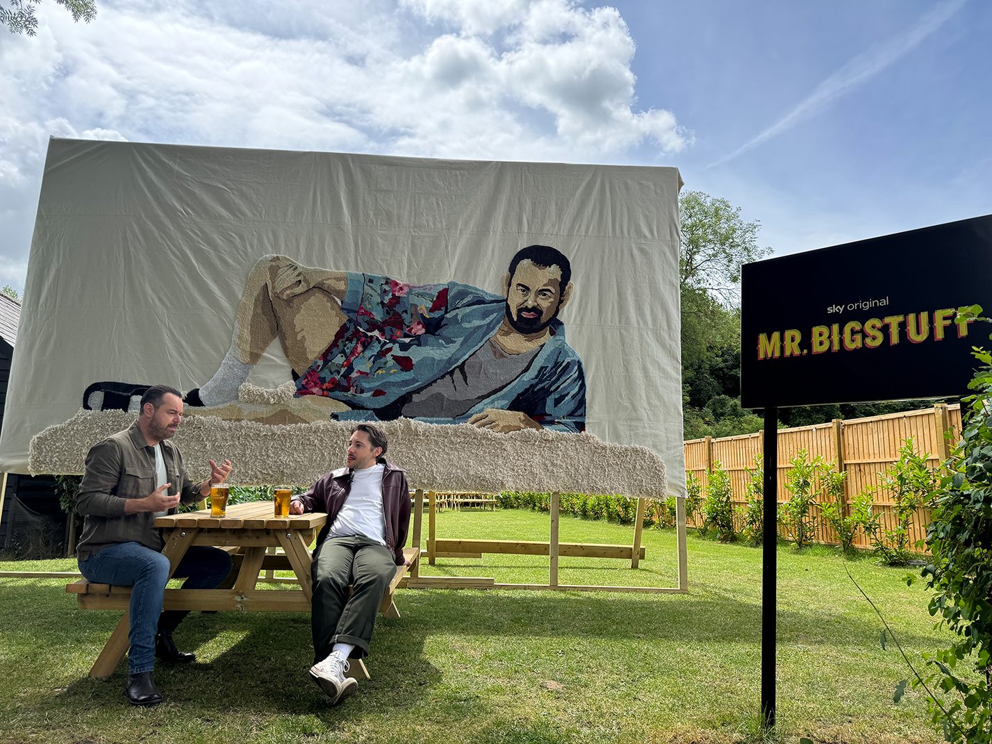 Danny Dyer and Ryan Sampson beside the giant portrait rug